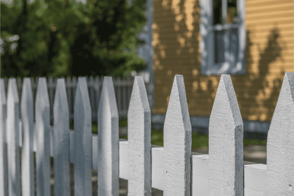 A white picket fence with a horizontal wooden rail