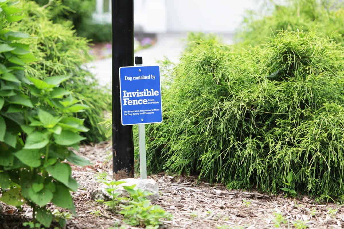An Invisible Fence brand sign at a suburban residence. The purpose of an invisible fence is to prevent a trained dog from leaving a specific area. 