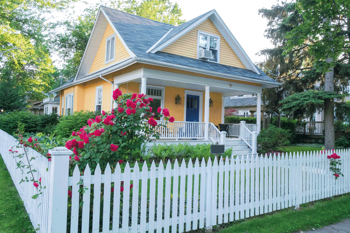 Pink Rose Bush in Front of a Beautiful Yellow House with a White Picket Fence. Neighbor's Fence Leaning On My Property- What To Do