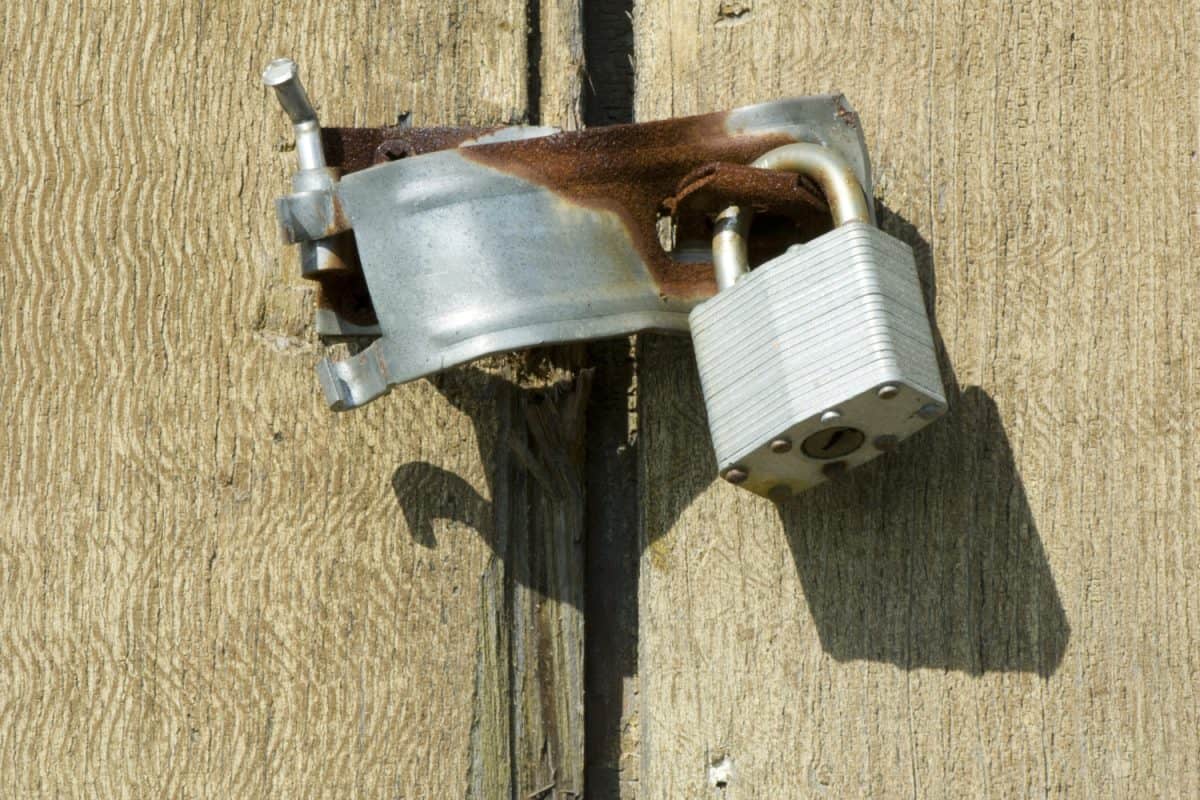 a broken latch attached to a padlock on an old door

