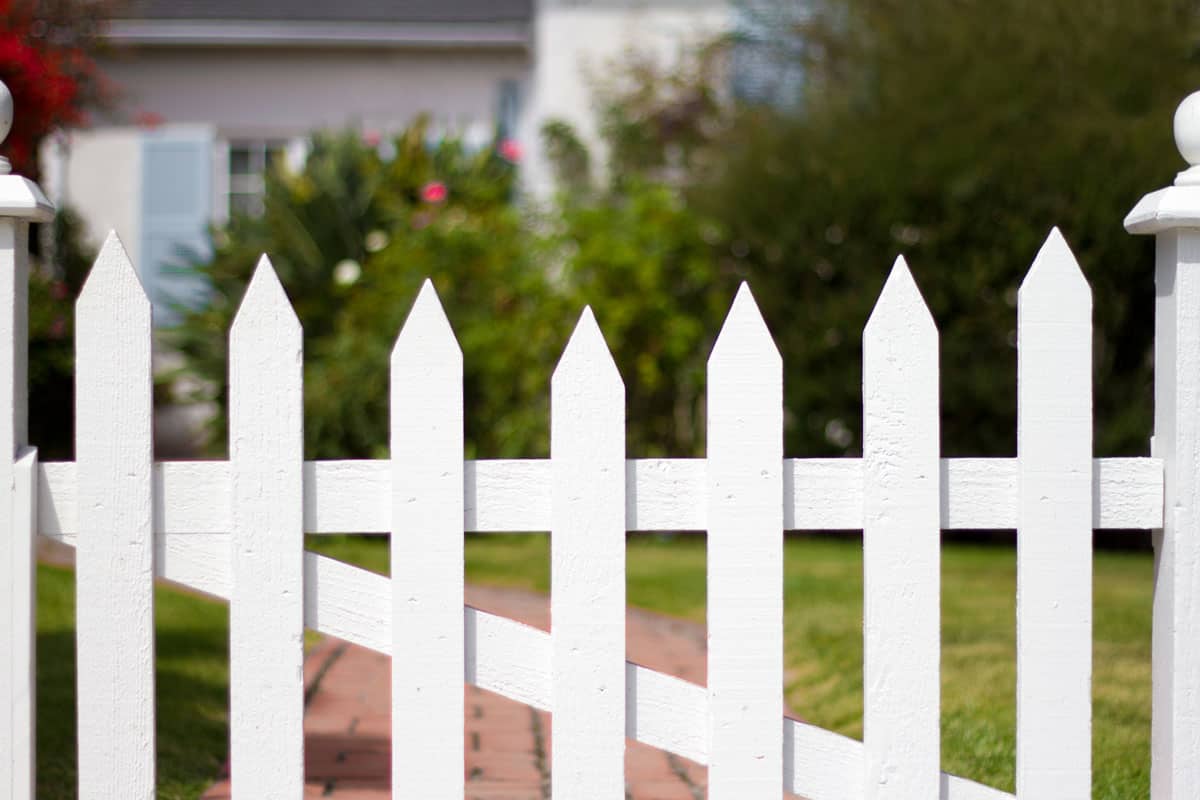bungalow with a white picket fence and garden