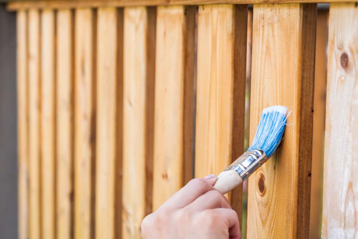 painting terrace railings with a blue paintbrush by hand

