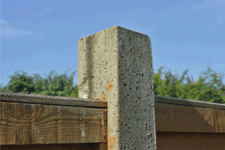 A concrete post holding a fence panel. Should You Paint Concrete Fence Posts