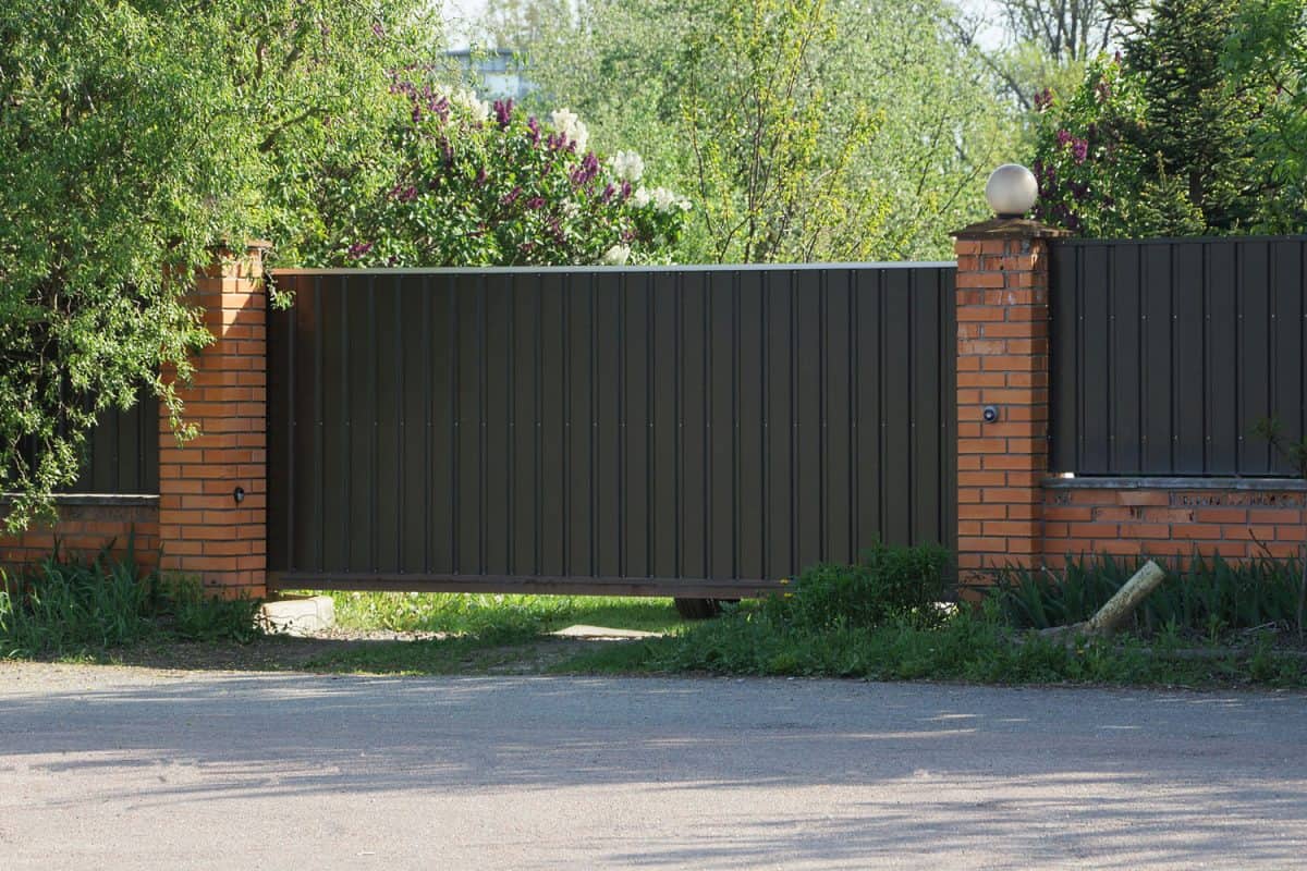 A long black sliding metal gate for a private high end property