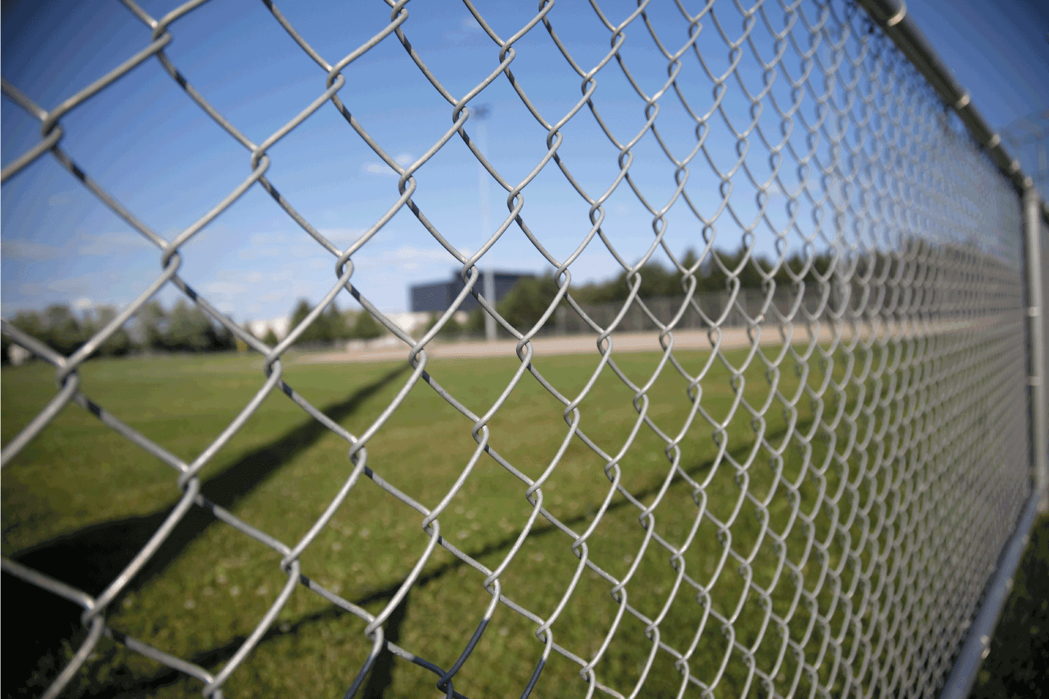 A picture of a chainlink fence on the side of a baseball field