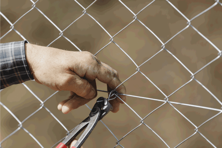 Construction worker building a fence. 4 Types Of Chain Link Fence Fabric And Gauges