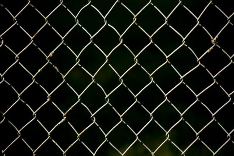 Full frame view of wire fence brightly lit, black background - How To Decorate A Chain-link Fence