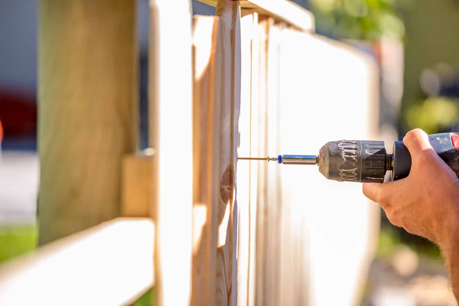 Man erecting a wooden fence outdoors