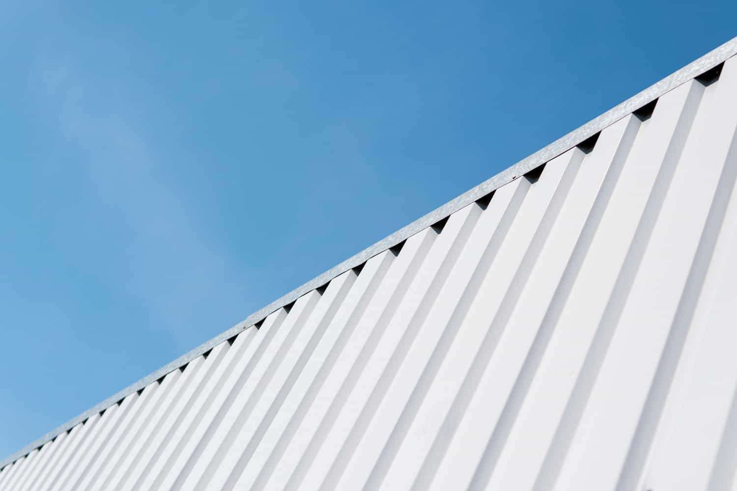 Metal white sheet for industrial building and construction on blue sky background. Roof sheet metal or corrugated roofs of factory building or warehouse