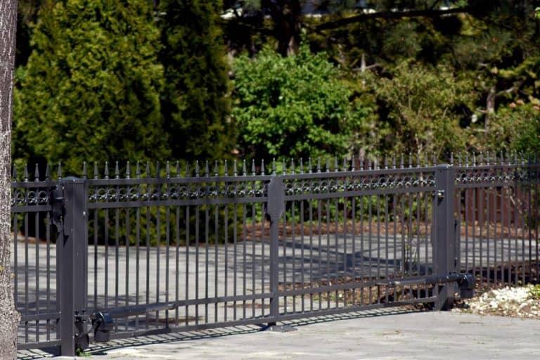 A metal garden fence painted in gray, Should Metal Fence Posts Be Set On Concrete?