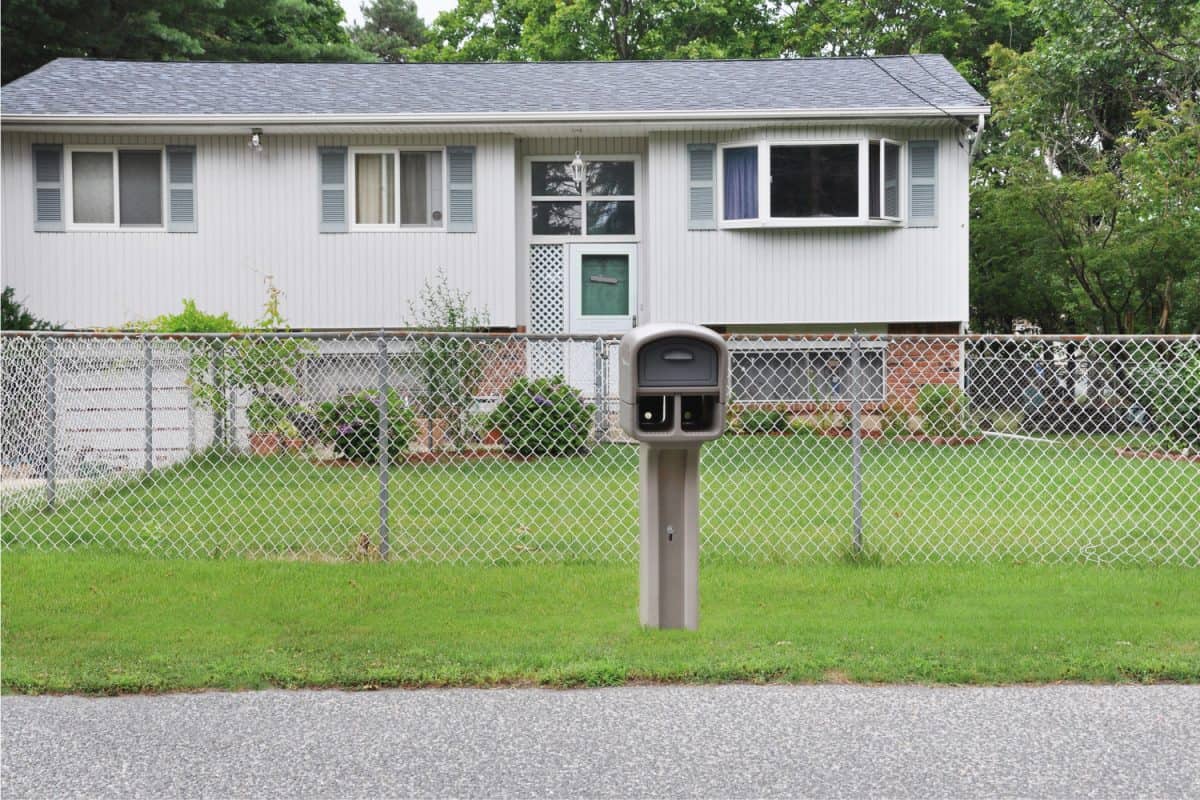 Suburban High Ranch style home with Chain link fence curbside Mailbox