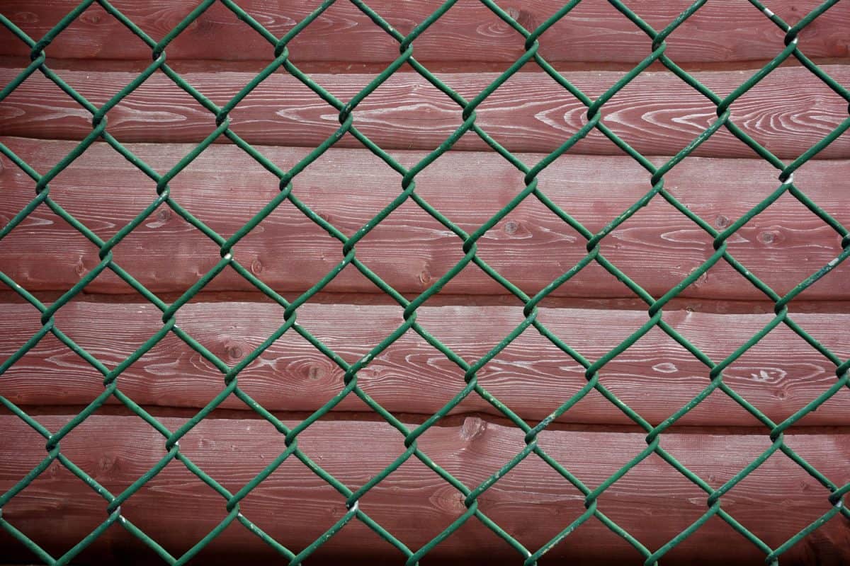 Wire mesh fence against the background of brown painted boards
