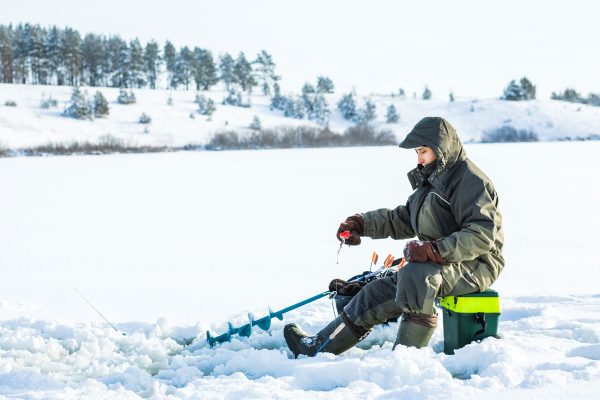 A young man is fishing from a hole on ice, Can You Use A Post-Hole Digger For Ice Fishing?