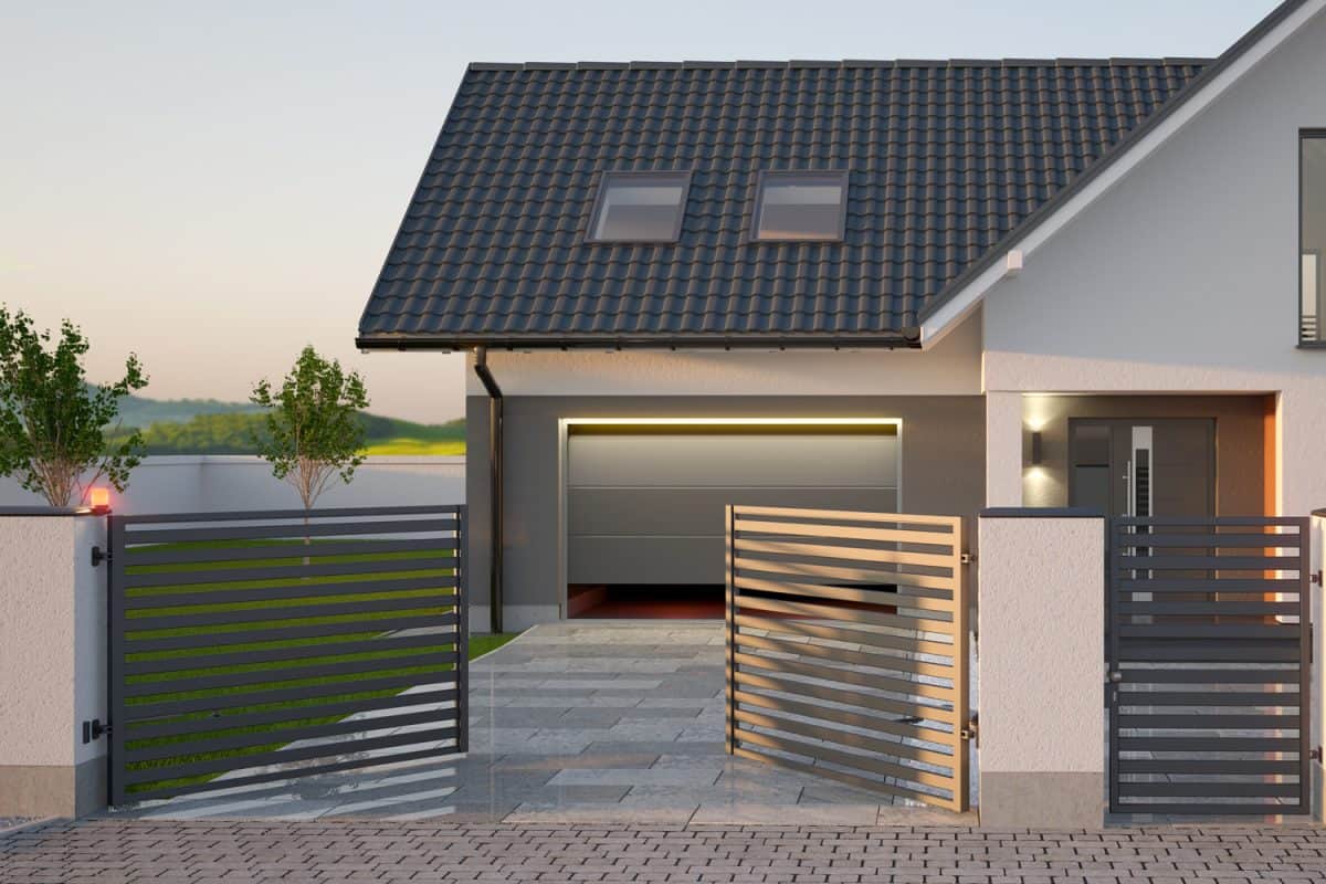 Automatic gate, fence, driveway and modern single family house with garage. 