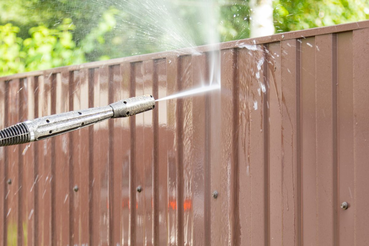 Cleaning fence with high pressure power washer, cleaning dirty wall.
