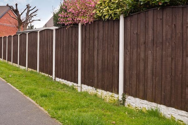 Close board fence erected around a garden for privacy with wooden fencing panels, concrete posts and kickboards for added durability, Are Gravel Boards Treated? [And How Long Do They Last]