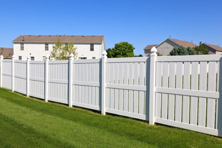 A new and contemporary white vinyl fence in a nicely landscaped back yard, Do Vinyl Fence Posts Need Wood Inserts? [Installation & Repair Tips]