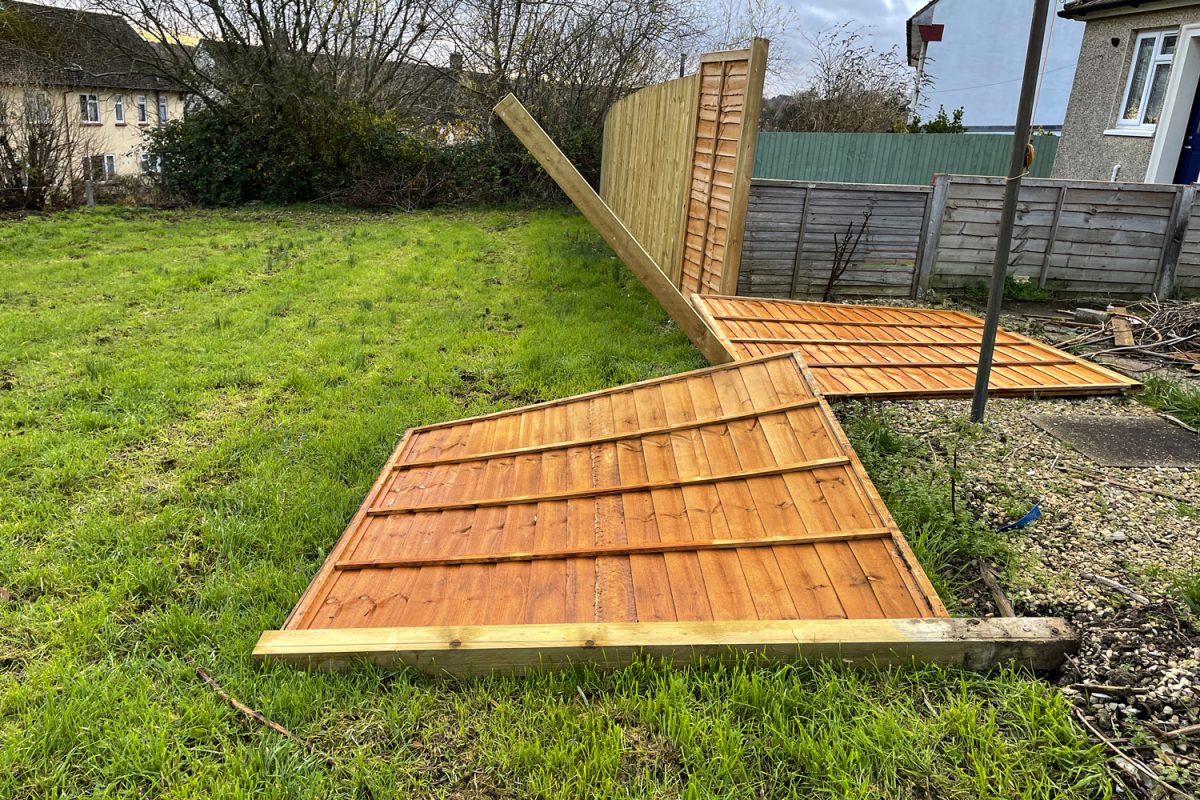 Stock photo showing fallen wooden panels of garden fence due to storm damage.


