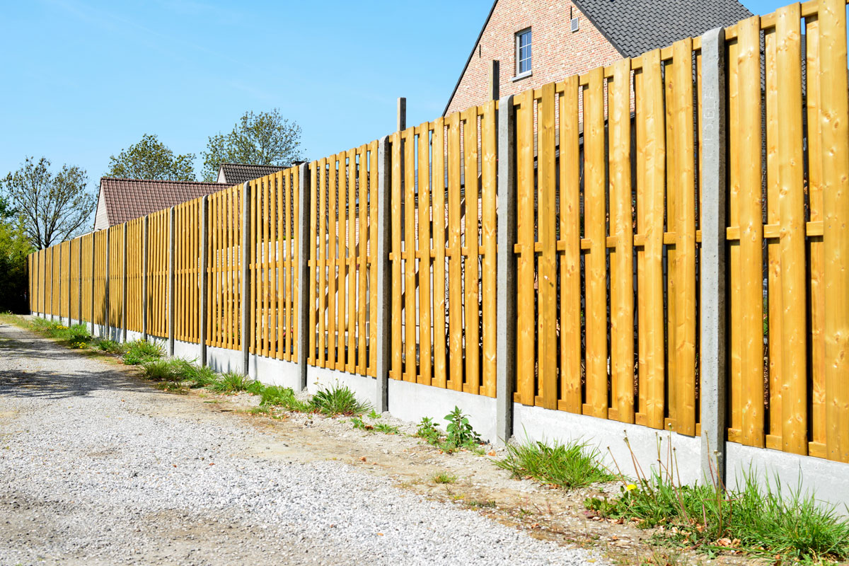 Tall light brown colored gravel board and concrete fence