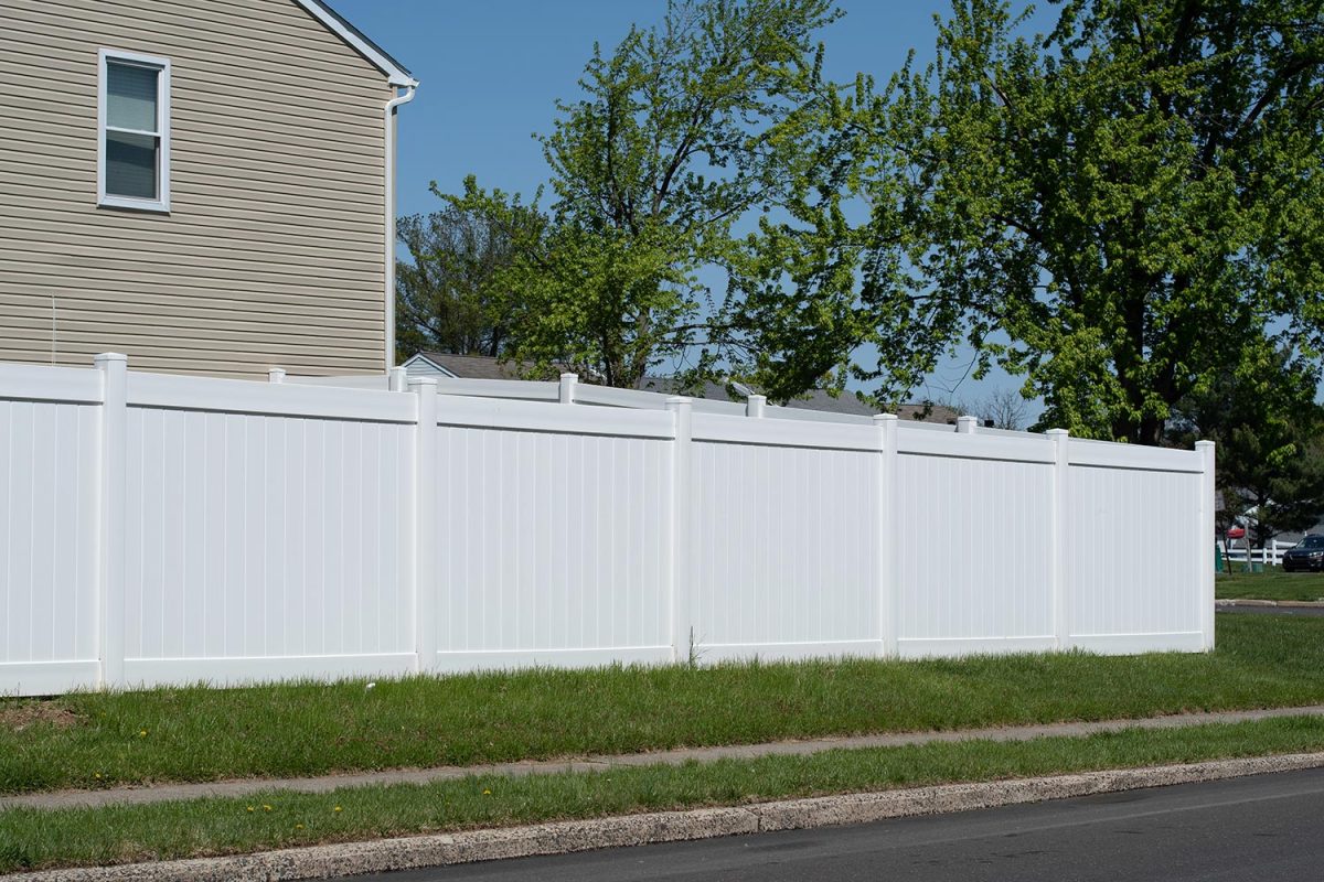 White vinyl fence in a cottage village fencing of private property grass plastic