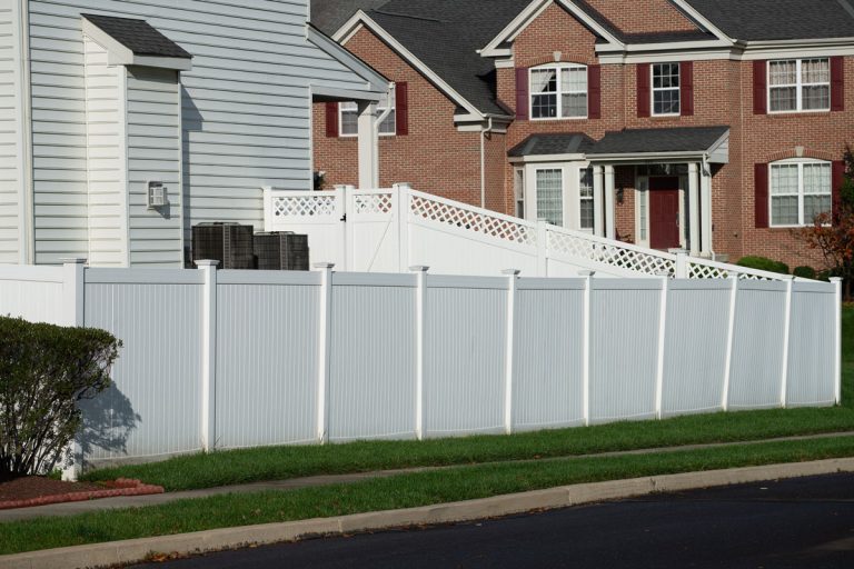 White vinyl fence in residential neighborhood home, Is Vinyl Fencing Good For Dogs: Reviewing The Pros & Cons For Your Pet's Security