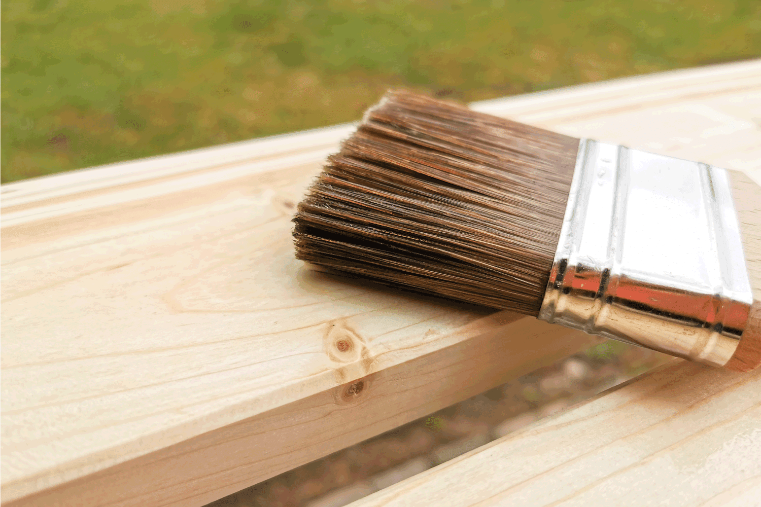 a paint brush lying on two pine wood boards. Should You Treat Split Rail Fence