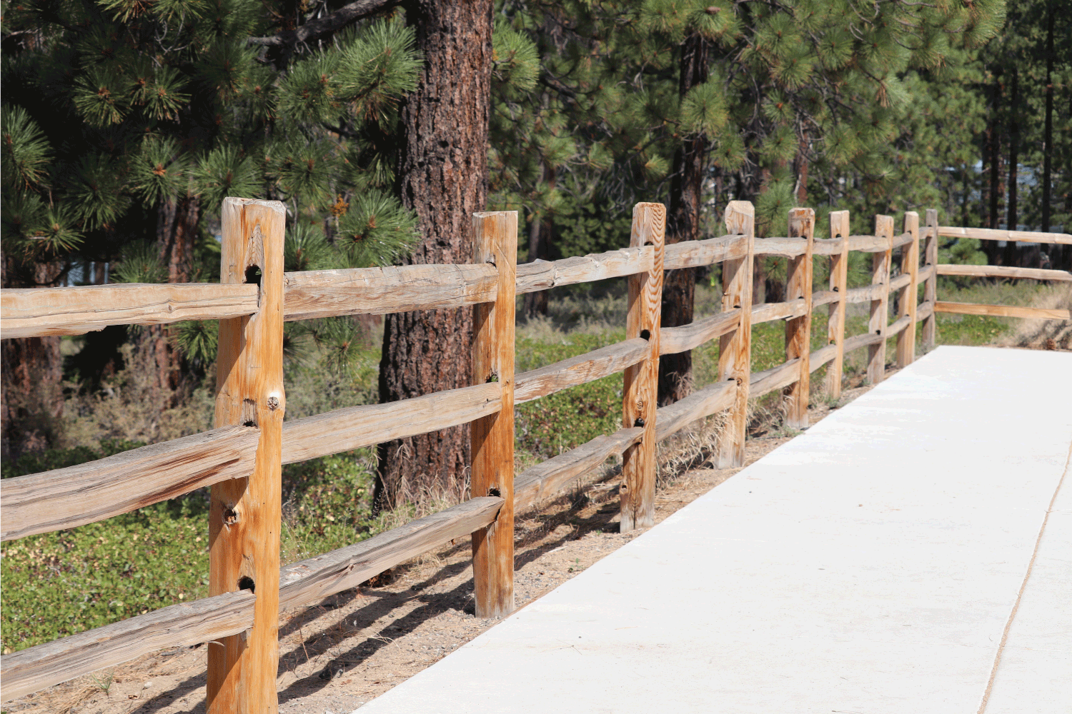 split rail fence wooden wood three 3 high next to sidewalk